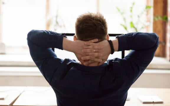 Relaxed businessman, sitting on chair, putting hands behind head and resting. (File photo)