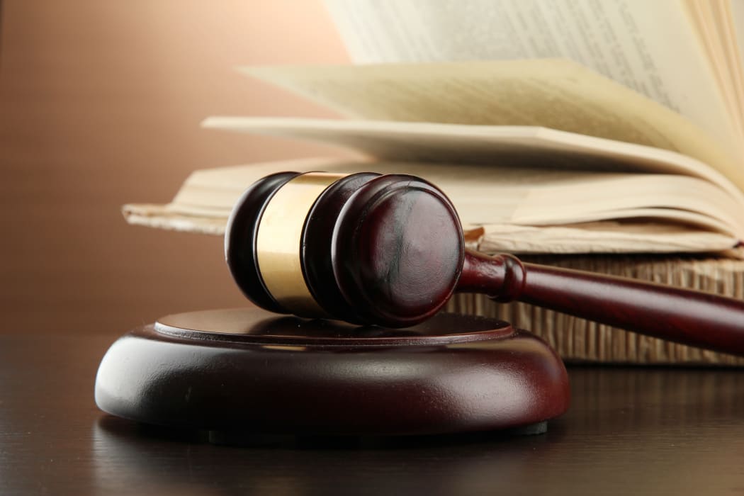 Wooden gavel and books on wooden table,on brown background
