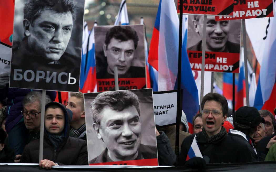Opposition supporters carry placards of Boris Nemtsov reading: "Fight", "These bullets in each of us", "He fought for our future" and "Heroes never die".