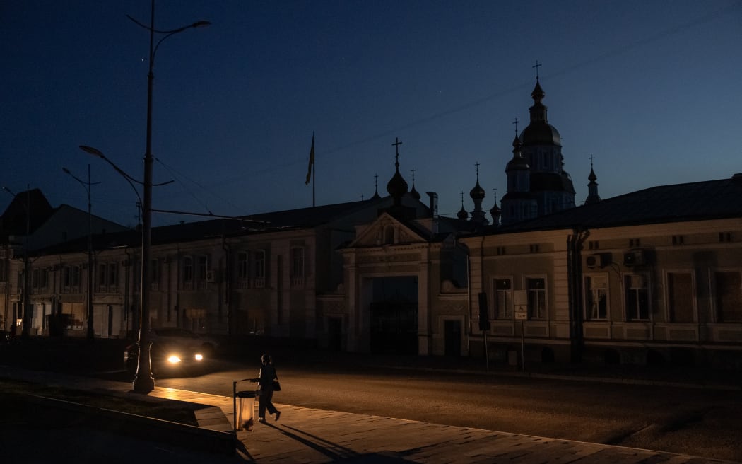 A person walks in a street during a blackout following Russian attacks on a city's energy infrastructure in Kharkiv, on April 8, 2024, amid the Russian invasion of Ukraine. (Photo by Roman PILIPEY / AFP)