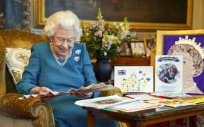 Queen Elizabeth II looking at Queen Victoria's Autograph fan, alongside a display of memorabilia from her Golden and Platinum Jubilees, in the Oak Room at Windsor Castle, west of London in January 2022.