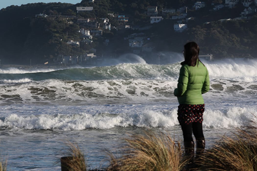 A passer-by watches high waves roll in during a storm surge at Lyall Bay on Wellington's South Coast.