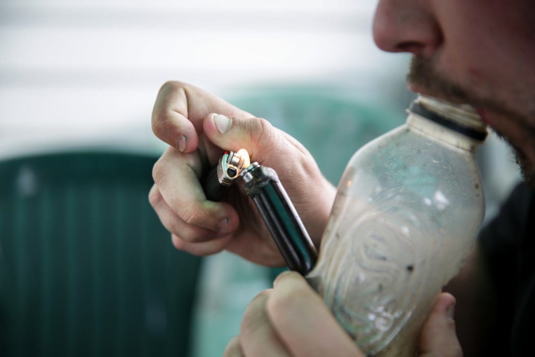 A male smoking using a homemade bong.
