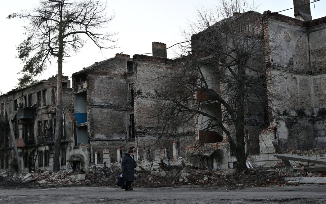 A local resident walks in front of a destroyed residential building in the town of Lyman, Donetsk region, on 14 December, 2022, amid the Russian invasion of Ukraine.