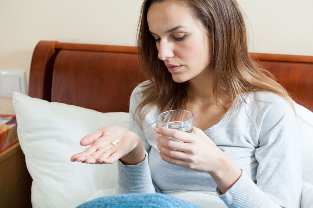 Woman with flu taking pills