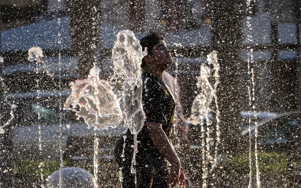 A young boy plays in a fountain to cool off during a heat wave, at the Mubarakiya Market in Kuwait City on August 5, 2023. (Photo by YASSER AL-ZAYYAT / AFP)