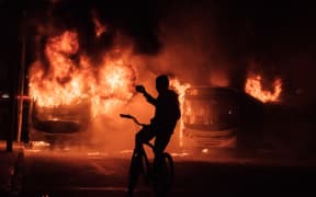 A man on a bicycle takes pictures of buses that were set on fire by protesters during the nationwide strike called by unions opposing austerity reforms in Rio de Janeiro, Brazil, on April 28, 2017.