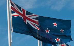 A New Zealand flag against a blue sky
