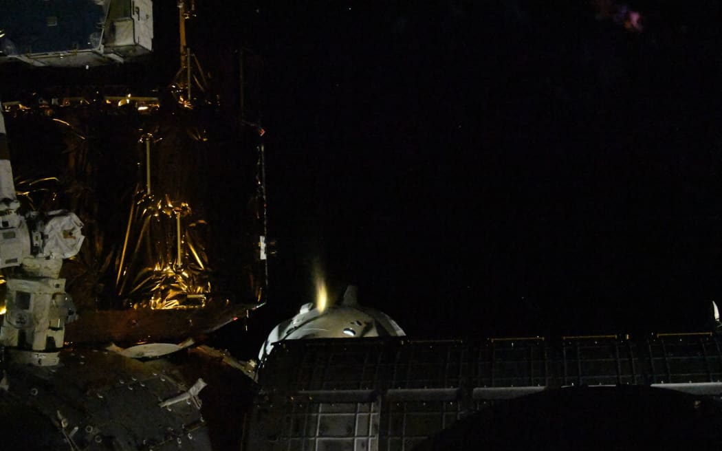 This handout picture released courtesy of NASA shows SpaceX Crew Dragon Endeavour firing one of its thrusters to back away from the International Space Station photographed by Space Station Commander Chris Cassidy on August 1, 2020.