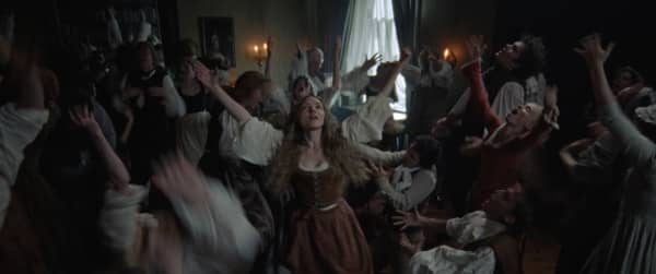 Amanda Seyfried leads a group of people in an ecstactic-looking dance.