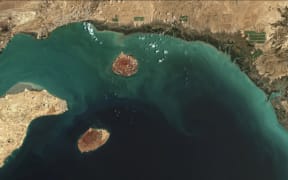 A satellite image of the northern part of the Strait of Hormuz, a vital shipping lane through the Gulf, showing the islands of Hormuz (right), Larak (centre), and Qeshm (left).