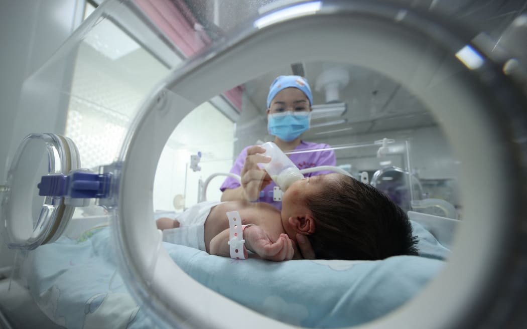 A medical staff member feeds a baby at a hospital in Danzhai, in China's southwestern Guizhou province on May 11, 2021.