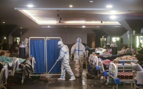 A health worker wearing a personal protective equipment suit cleans the floor inside a banquet hall temporarily converted into a Covid-19 coronavirus ward in New Delhi