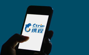 A Chinese mobile phone user shows a logo of online travel search service Ctrip,  which has more than 300 million registered users.