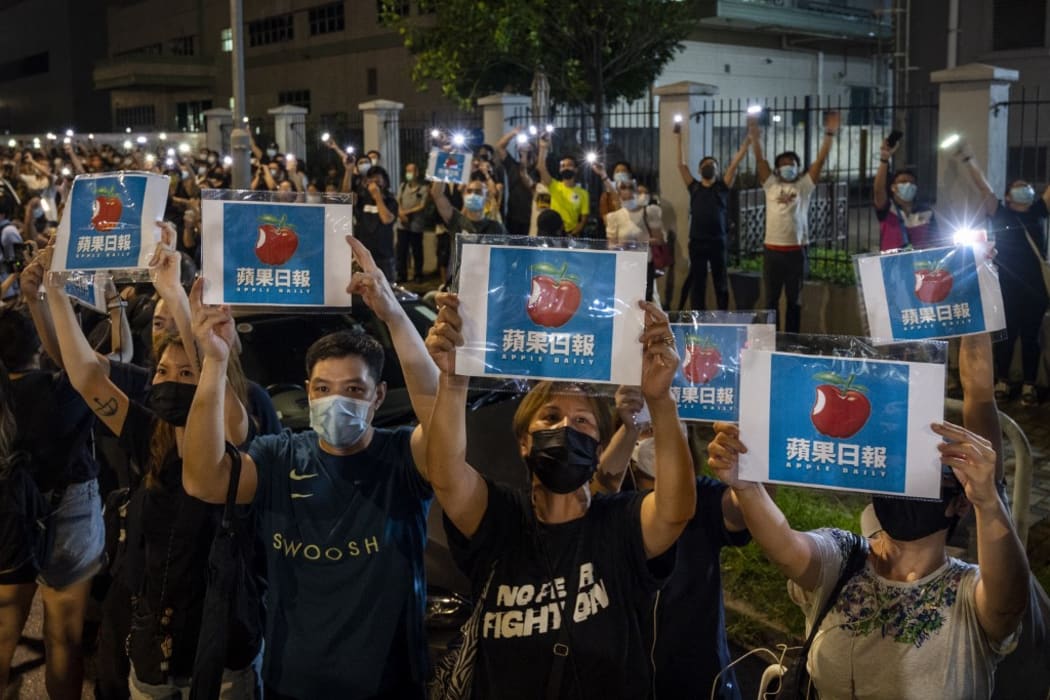 HONG KONG - JUNE 23: Supporters use their their smartphone torches and placards with Apple Daily logos towards the Apple Daily workers outside the headquarters of the Apple Daily newspaper in Hong Kong on June 24, 2021.