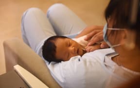 A nurse holds a baby at the Xiyuege Centre, or "Lucky Month Home", in Beijing. Concerns about slow population growth led to a three-child policy in May this year.