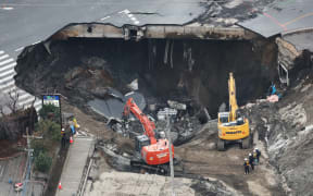 An aerial photo shows the site of a road collapsed above huge sinkholes at an intersection in Yashio City, Saitama Prefecture, adjacent to Tokyo on February 2, 2025. The hole appeared on Jan. 28th, and swallowed a truck and a driver. The search effort for the 74-year-old man remains suspended after a quantity of water was found in the hole. The cause of the road collapse is believed to be the breakage of an old sewer pipe.   ( The Yomiuri Shimbun ) (Photo by Daisuke Urakami / Yomiuri / The Yomiuri Shimbun via AFP)