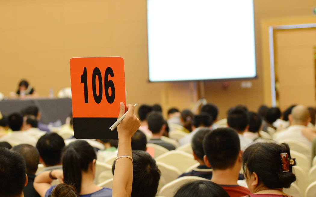 People holding auction paddle to buy from auction.