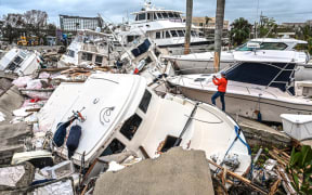 A man takes photos of boats damaged by Hurricane Ian in Fort Myers, Florida, on September 29, 2022. - Hurricane Ian left much of coastal southwest Florida in darkness early on Thursday, bringing "catastrophic" flooding that left officials readying a huge emergency response to a storm of rare intensity. The National Hurricane Center said the eye of the "extremely dangerous" hurricane made landfall just after 3:00 pm (1900 GMT) on the barrier island of Cayo Costa, west of the city of Fort Myers. (Photo by Giorgio VIERA / AFP)