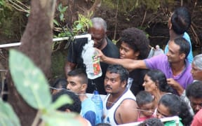 People crowd to fill bottles with water from the Natadradave stream.