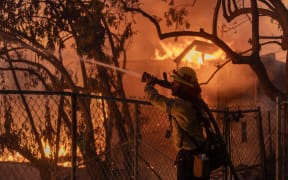 Los Angeles County firefighter battles flames as a home burns from the Mountain Fire on 6 November 2024 in Camarillo, California.