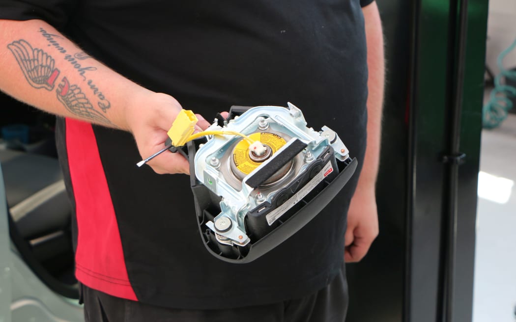 A mechanic removes an airbag from a car.