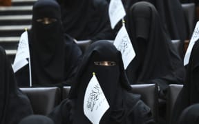 Veiled students hold Taliban flags as they listen to a speaker before a pro-Taliban rally at the Shaheed Rabbani Education University in Kabul on 11 September 2021.