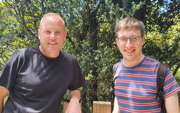 Ecologists with an interest in epiphytes: KC Burns and Tom Dawes stand in front of a climbing rata growing up a larger tree.