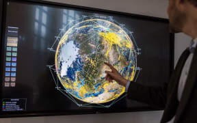 A worker points to a monitor displaying current satellites in orbit and real-time communications across the globe at the Iridium Communications Inc. Satellite Network Operations Center in Leesburg, Virginia.