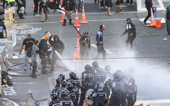 Protesters gain control of a fire hose and aim that at police as well