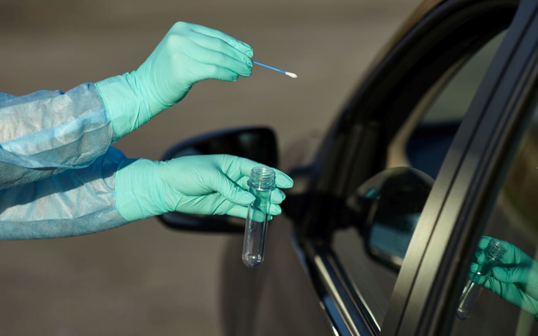 Epidemic concept COVID-19. Coronavirus Test Station. 
Medical worker in full protective gear takes sample from patient at a COVID-19 drive-thru test site.