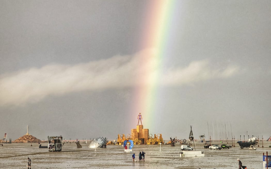 This handout image provided courtesy of Josh Lease on September 3, 2023 shows a rainbow over flooding on a desert plain on September 1, 2023, after heavy rains turned the annual Burning Man festival site in Nevada’s Black Rock desert into a mud pit. Tens of thousands of drenched festivalgoers were stranded on September 3, 2023, in deep, sticky mud in the Nevada desert after torrential rain turned the annual Burning Man gathering into a quagmire. All events at the counterculture festival, which drew some 70,000 people, were canceled after rain tore down structures for dance parties, art installations and other eclectic entertainment. (Photo by Josh Lease / UGC / AFP) / RESTRICTED TO EDITORIAL USE - MANDATORY CREDIT "AFP PHOTO / Josh Lease" - NO MARKETING NO ADVERTISING CAMPAIGNS - DISTRIBUTED AS A SERVICE TO CLIENTS