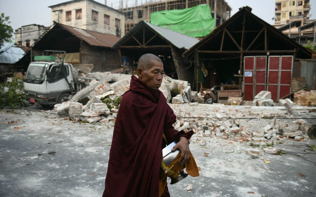A monk walks past damaged houses in Mandalay on March 30, 2025, two days after an earthquake struck central Myanmar.