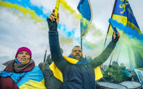 A man holds flares with the colors of the ukrainian flag in a nationalist march along the Paton bridge during the celebration of the Day of Unity in Kiev
