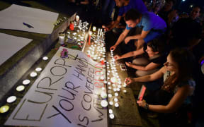 People light candles in Budapest next to a banner reading 'Europe,your hand is covered with blood' in Budapest to commemorate 71 dead migrant victims found in a truck in Austria.