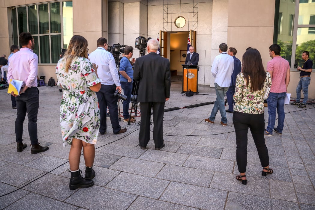 Members of the media stand apart as they listen to Australian Prime Minister Scott Morrison (C) speak during a press conference at Australia's Parliament House in Canberra on March 22