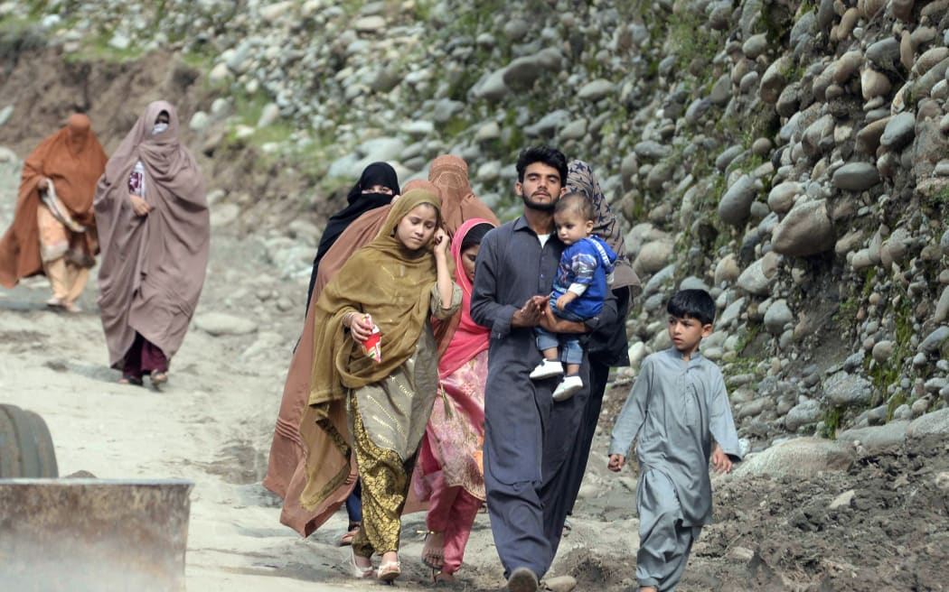 SWAT, PAKISTAN - AUGUST 29: Displaced people walk to a safer area following the deadly climate catastrophe in the Swat Valley, Khyber Pakhtunkhwa province, Pakistan on August 29, 2022. Pakistan's flooding emergency threatens to leave a third of the country underwater while flash floods triggered by destructive monsoon rains have killed more than 1,000 people and injured thousands more since June. Zubair Abbas / Anadolu Agency (Photo by Zubair Abbas / ANADOLU AGENCY / Anadolu Agency via AFP)