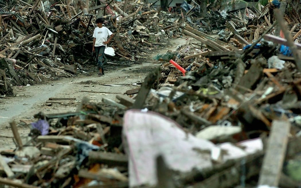 An Acehnese tsunami surviving young man walks along debris of houses in Banda Aceh, 29 January 2005.