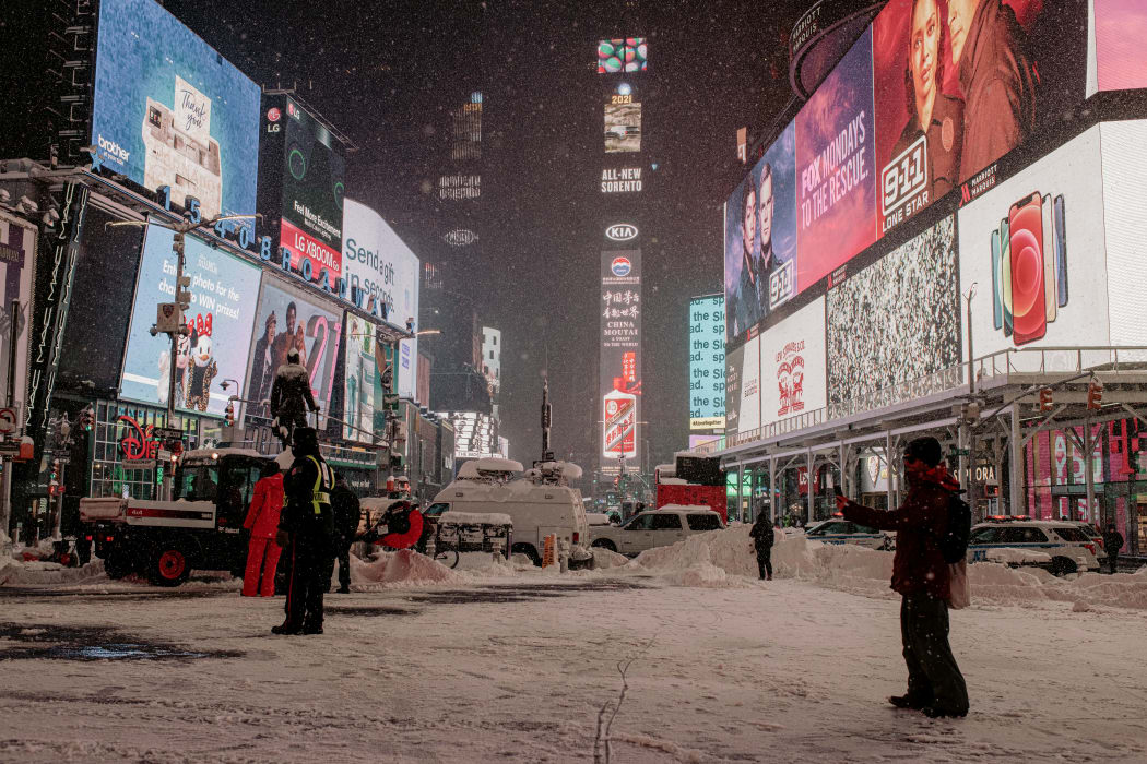 A man takes a photo as snow continues to fall in Times Square, NYC.