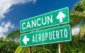 A traffic sign indicating the directions to  Cancun and the airport with arrows in Cancun, Mexico.