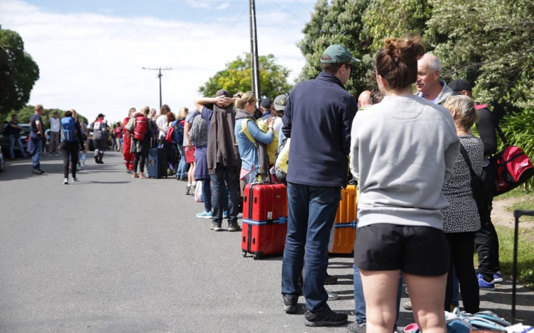 Tourists in Kaikoura queue to be taken to the navy ship off the coast of the quake-hit town.