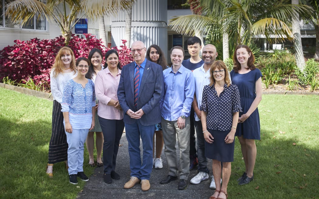 A wide shot of a group of 11 people standing in a garden.
