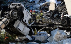 Rescuers inspect the rubble and wreckages by the Morandi motorway bridge.