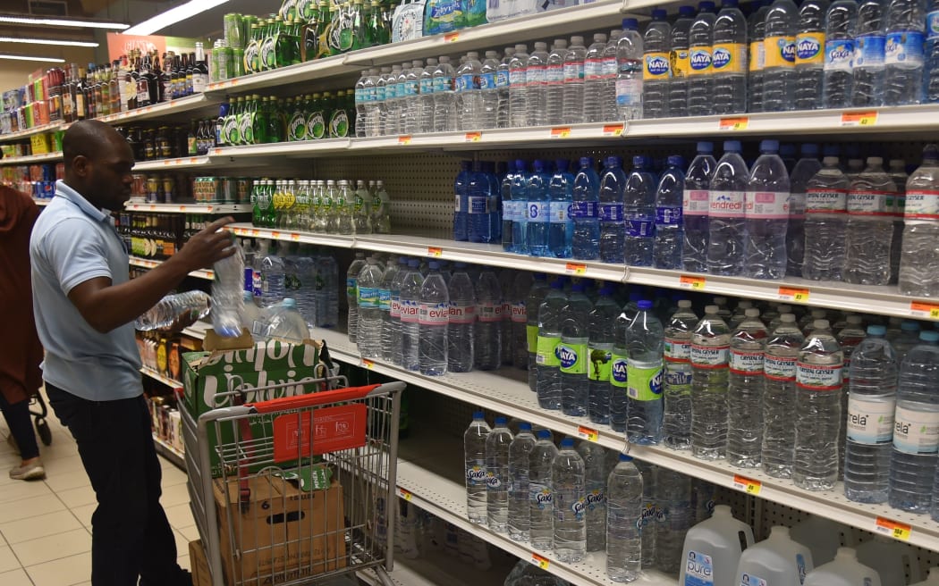 A worker fills shelves with water bottles at a supermarket in the commune of Petion Ville, in the Haitian Capital Port-au-Prince, on October 2, 2016.