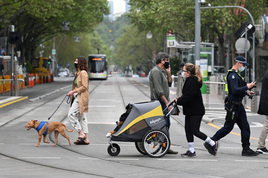 People walk their dogs in Melbourne on 30 September 2021 as the city grapples with a surge in Covid-19 infections.
