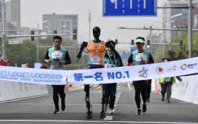Robotic participant "Tiangong Ultra"competes as engineers run alongside during the Beijing E-Town half-marathon and humanoid robots half-marathon in Beijing.