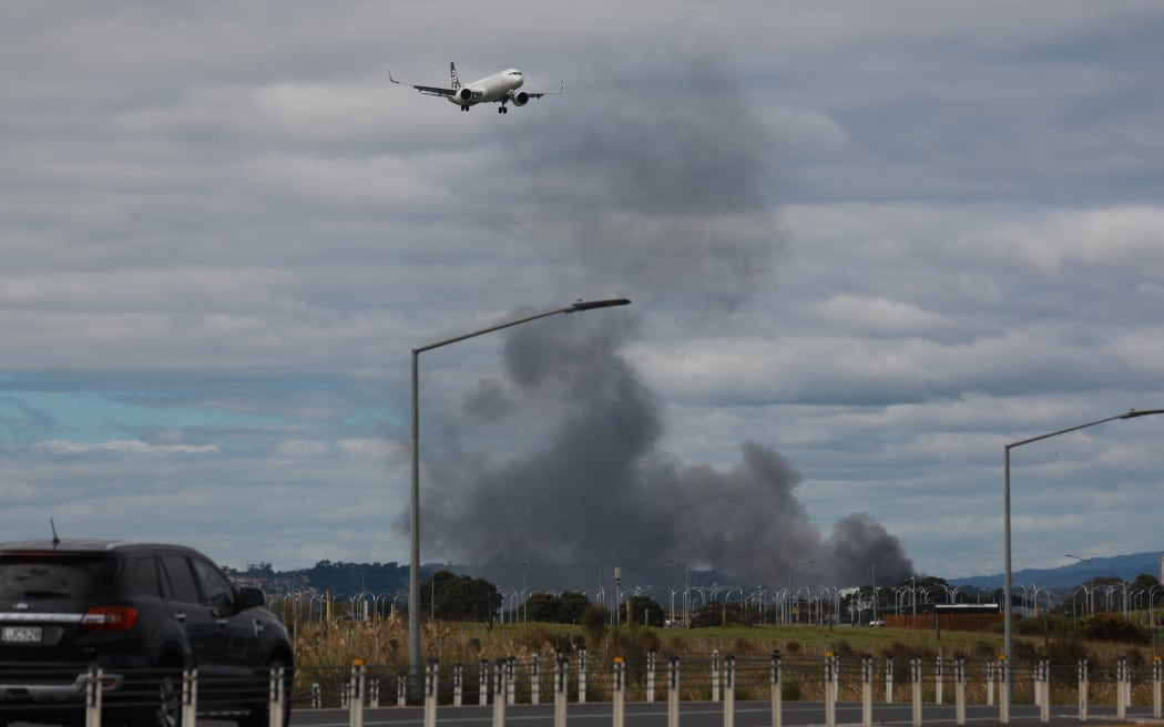 Smoke from a fire in Wiri with a plane flying over it.