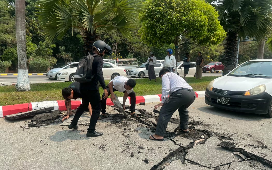 Motorists pick up pieces of a damaged road in Naypyidaw on March 28, 2025, after an earthquake in central Myanmar. A powerful earthquake rocked central Myanmar on March 28, buckling roads in capital Naypyidaw, damaging buildings and forcing people to flee into the streets in neighbouring Thailand. (Photo by AFP)