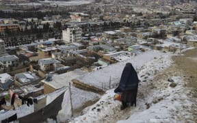 A burqa-clad woman walks down at a path in Afghanistan during a cold winter day in Fayzabad of Badakhshan province on 18 January, 2023. At least 70 people have died in a wave of freezing temperatures sweeping Afghanistan, officials said on 18 January, as extreme weather compounds a humanitarian crisis in the poverty-stricken nation.