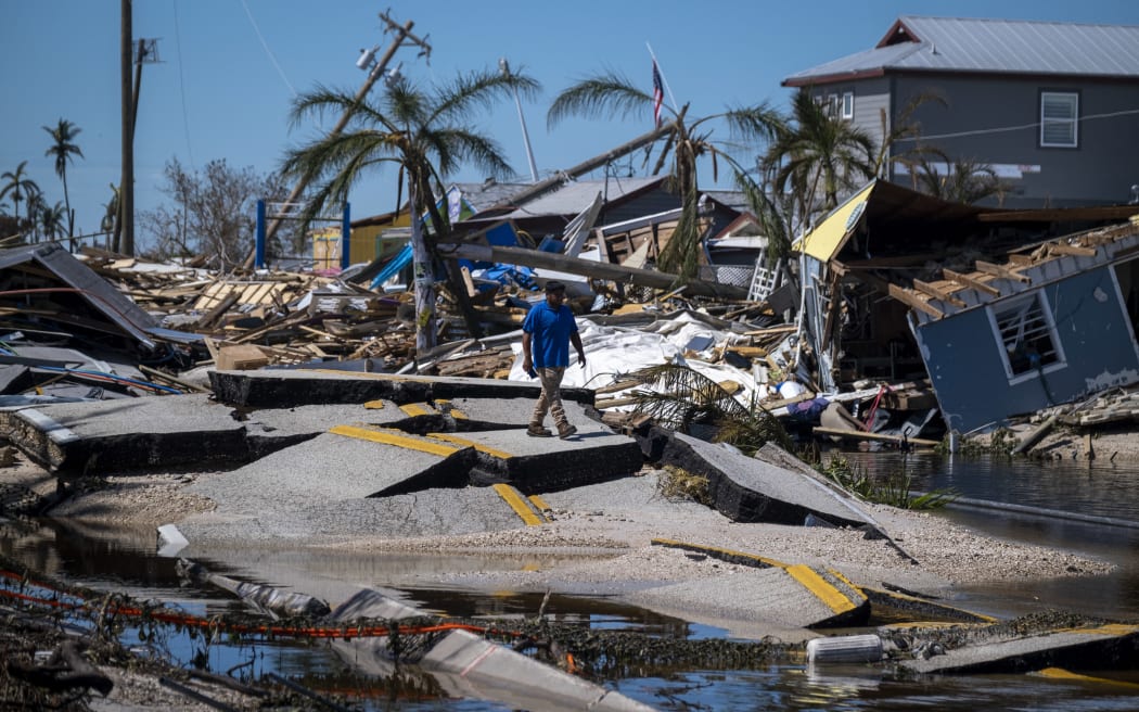 A man walks over a broken section of the Pine Island Road in the aftermath of Hurricane Ian in Matlacha, Florida on October 1, 2022.